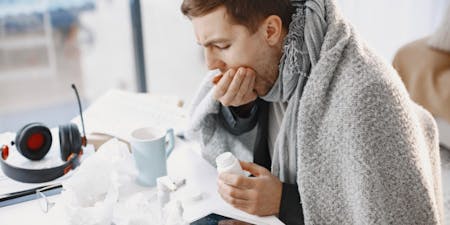 Man sick sitting at a table taking medicine