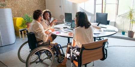 Person in wheelchair sat at around table with co-workers 