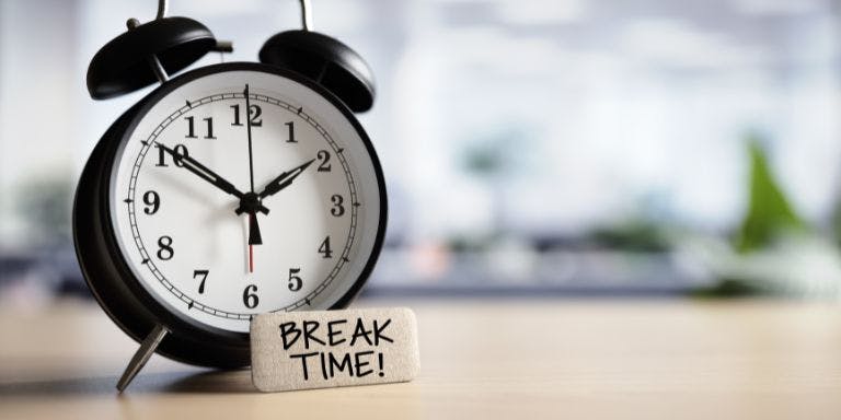 Break time at work A clock sitting on a desk with a note to take a break