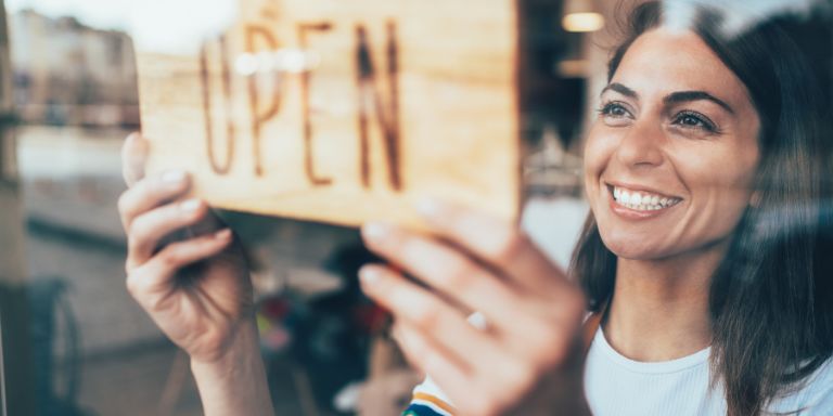Small business owner opening her shop front 