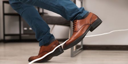 Trailing cables are a trip hazard A person tripping over a loose cable on the ground in an office