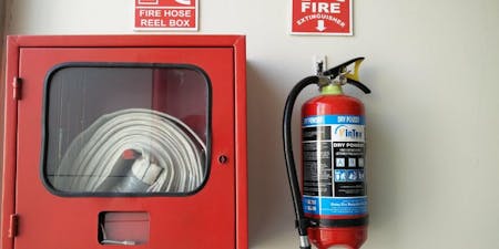 Fire safety measures in the workplace A fire hose and fire extinguisher placed on a wall for easy reach