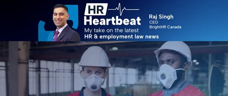 Two workers at a jobsite wearing reflective vests, hard hats and face masks