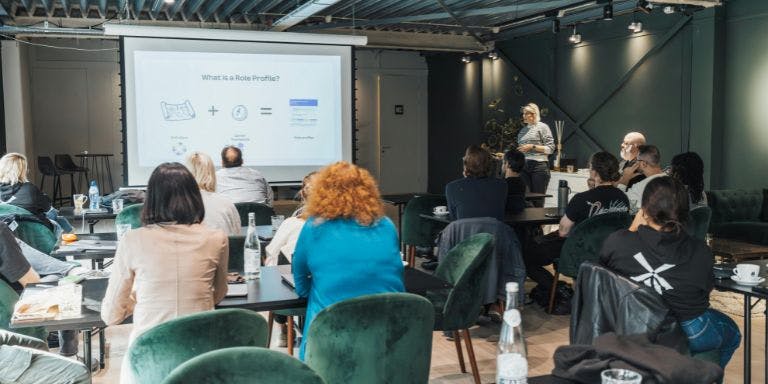 An employee training day held in a boardroom with a presenter and a smart screen display