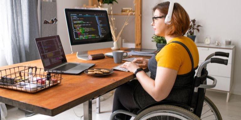 Employees with diasbilities A disabled employee using a wheelchair, working from home at her desk