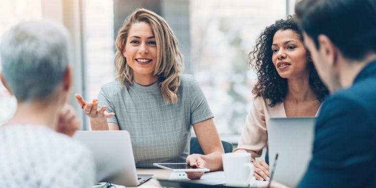 A manager leading a team meeting with employees around a meeting table