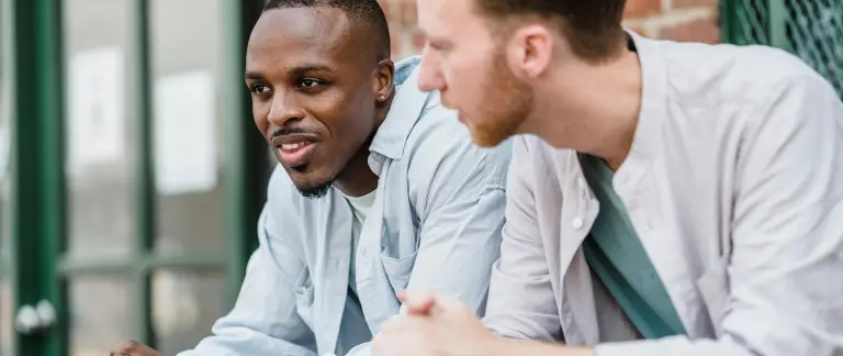 Two men are sitting on a bench, engaged in a conversation.