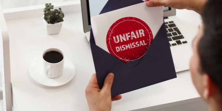 a person opening a letter with the words "unfair dismissal" on the paper in a red and white stamp
