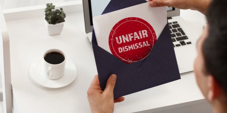 a person opening a letter with the words "unfair dismissal" on the paper in a red and white stamp