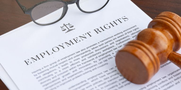 A wooden gavelle with a pair of glasses resting on top of it is placed on a piece of paper.