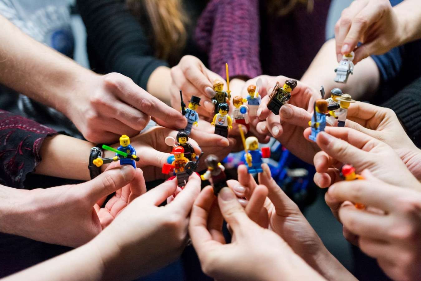 group of people holing lego models in their hands group of people holing lego models in their hands