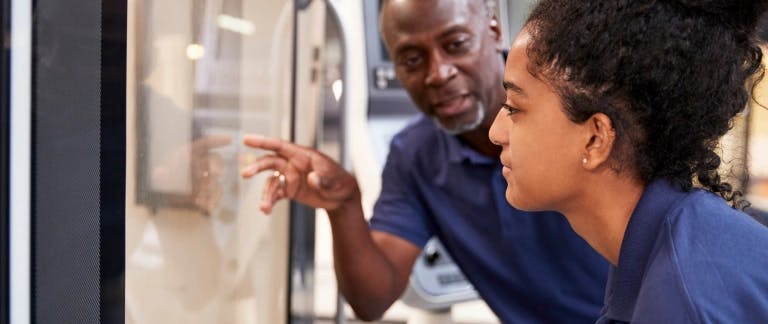 A picture of a man talking to a young woman while she looks through a window