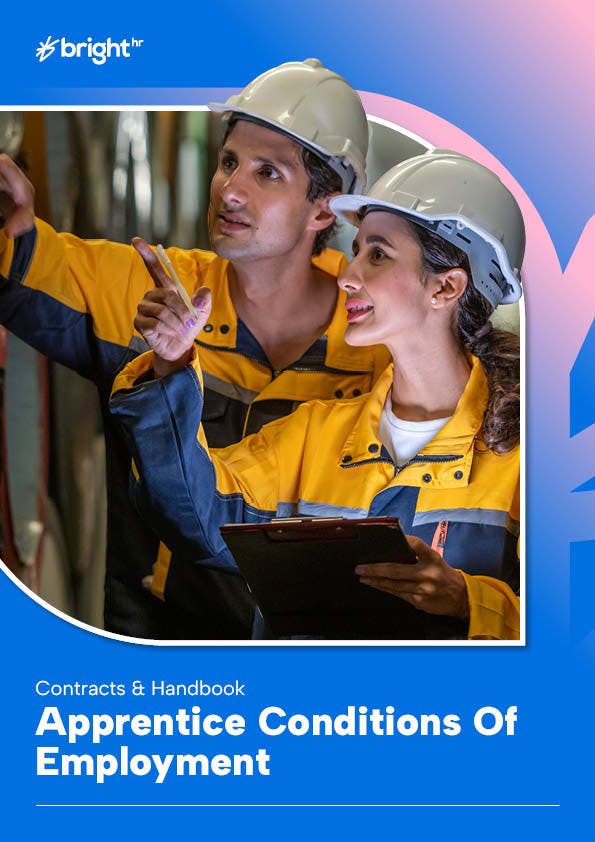 The image features a man and a woman, both wearing hard hats, engaged in a conversation. The man is pointing towards something, while the woman is pointing towards a clipboard.