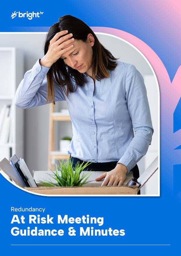 Image of a woman standing in front of a desk with a plant and a stack of papers.