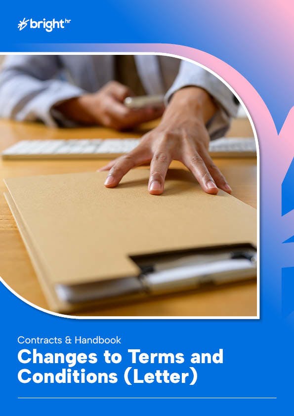 A person's hand is seen resting on a brown notebook, which is placed on a wooden desk.
