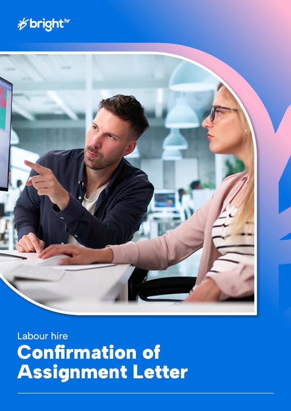 The image features a man and a woman in an office setting. The man is pointing at a computer screen, suggesting some form of interaction or discussion. The woman is seated at a desk, attentively listening to the man's point.