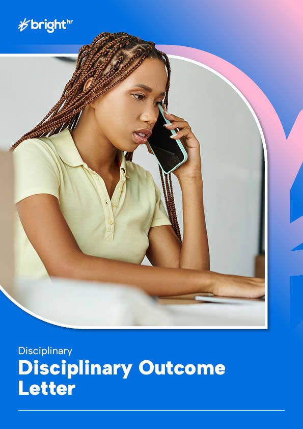 A young woman with braided hair is seated at a desk, engrossed in a phone call. She is wearing a light-colored polo shirt and is holding a phone to her ear.
