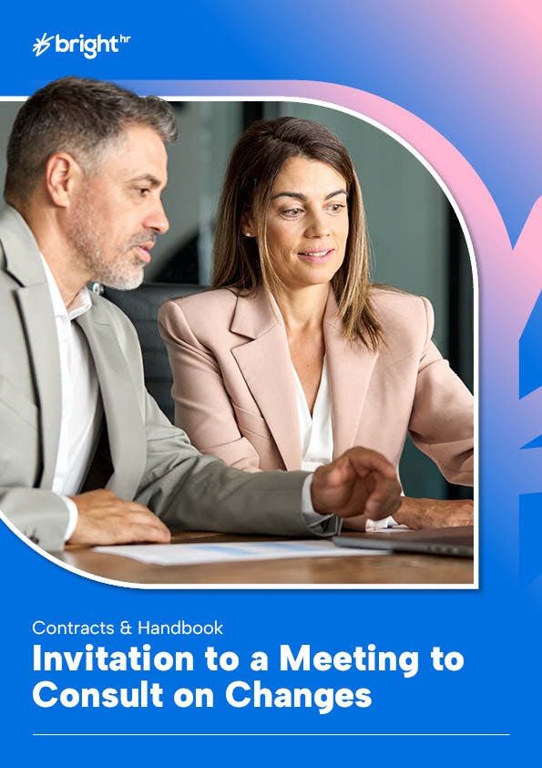 Two employees having a conversation while looking at a laptop