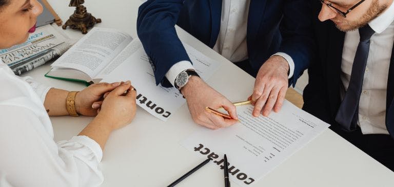 Staff and candidate at desk signing employment contract