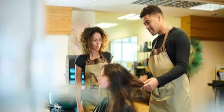 Apprentice Hair Stylist An apprentice hair stylist styling a client while the salon owner oversees their work