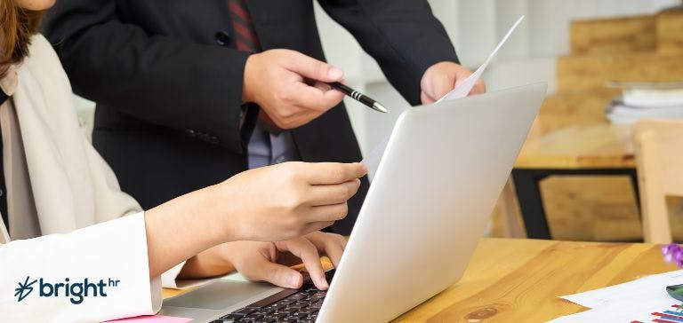 Shifts and rostering software Staff on desk looking at data on laptop with reports
