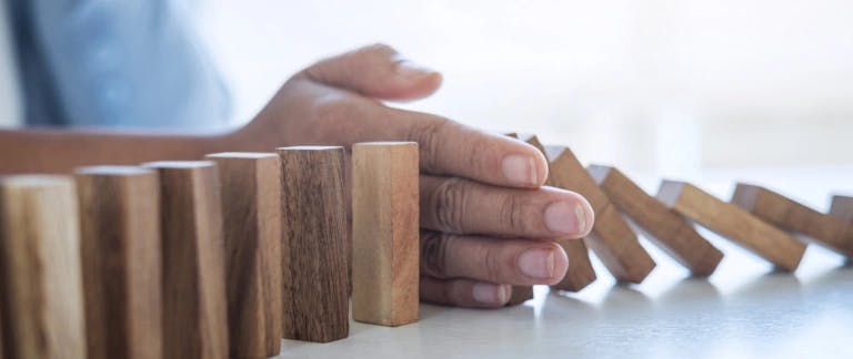Preventing harassment A person's hand is stopping dominos from falling