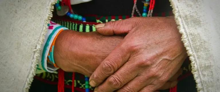 A person in Indigenous Canadian dress clasping their hands together