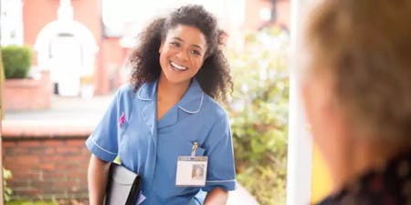 Adult Social Care A carer knocking on the door of a patient, greeting them with a friendly face, wearing a typical carer's uniform with a name badge and bag
