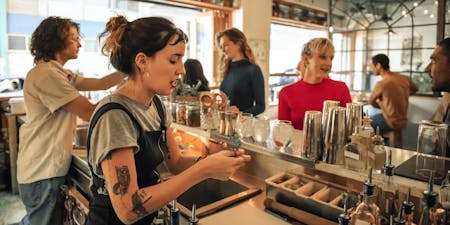 two bartenders making cocktails for a small group of patrons.