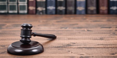 a gavel on a wooden table with some hardback books behind.