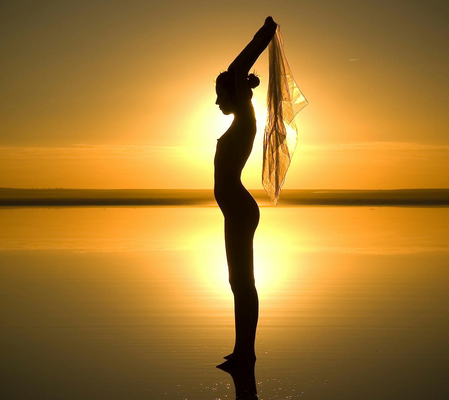 Silhouette of a naked woman in front of the sunset.