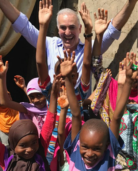 Dr. Alizadeh and children happy with hands raised.