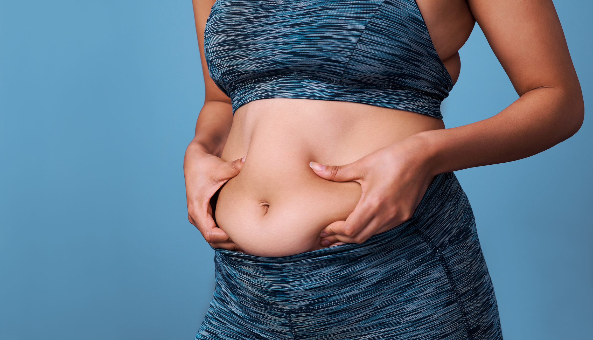 Woman pinching her belly fat.