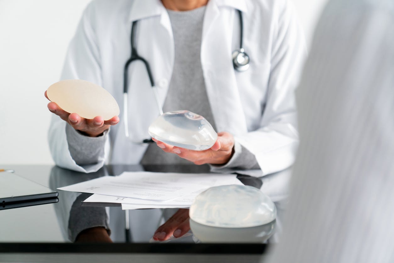 doctor holding different types of breast implants