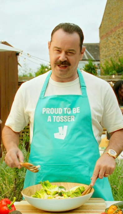 Danny Dyer in a Proud To Be A Tosser apron tossing a salad for Deliveroo