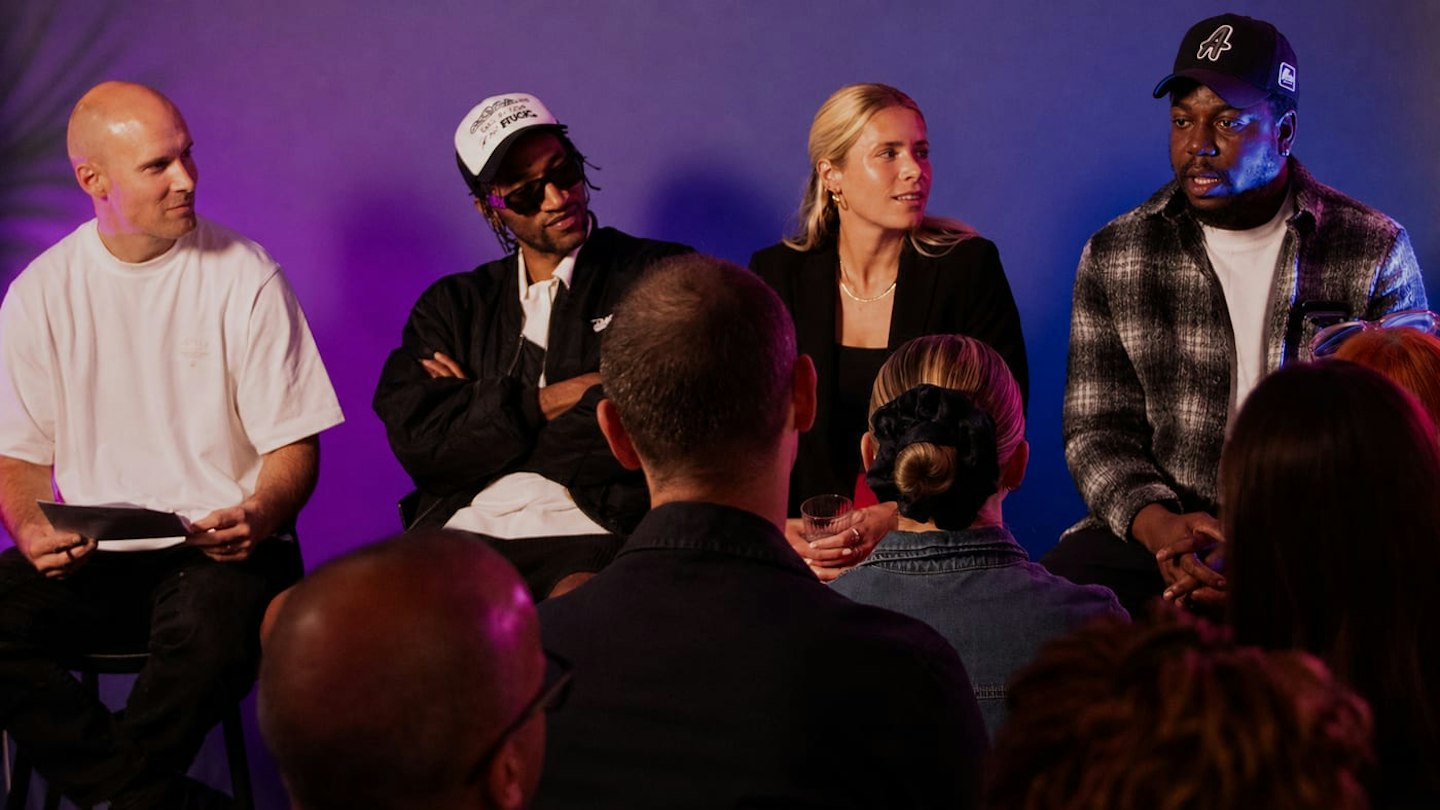 Panel of speakers on a purple-lit stage