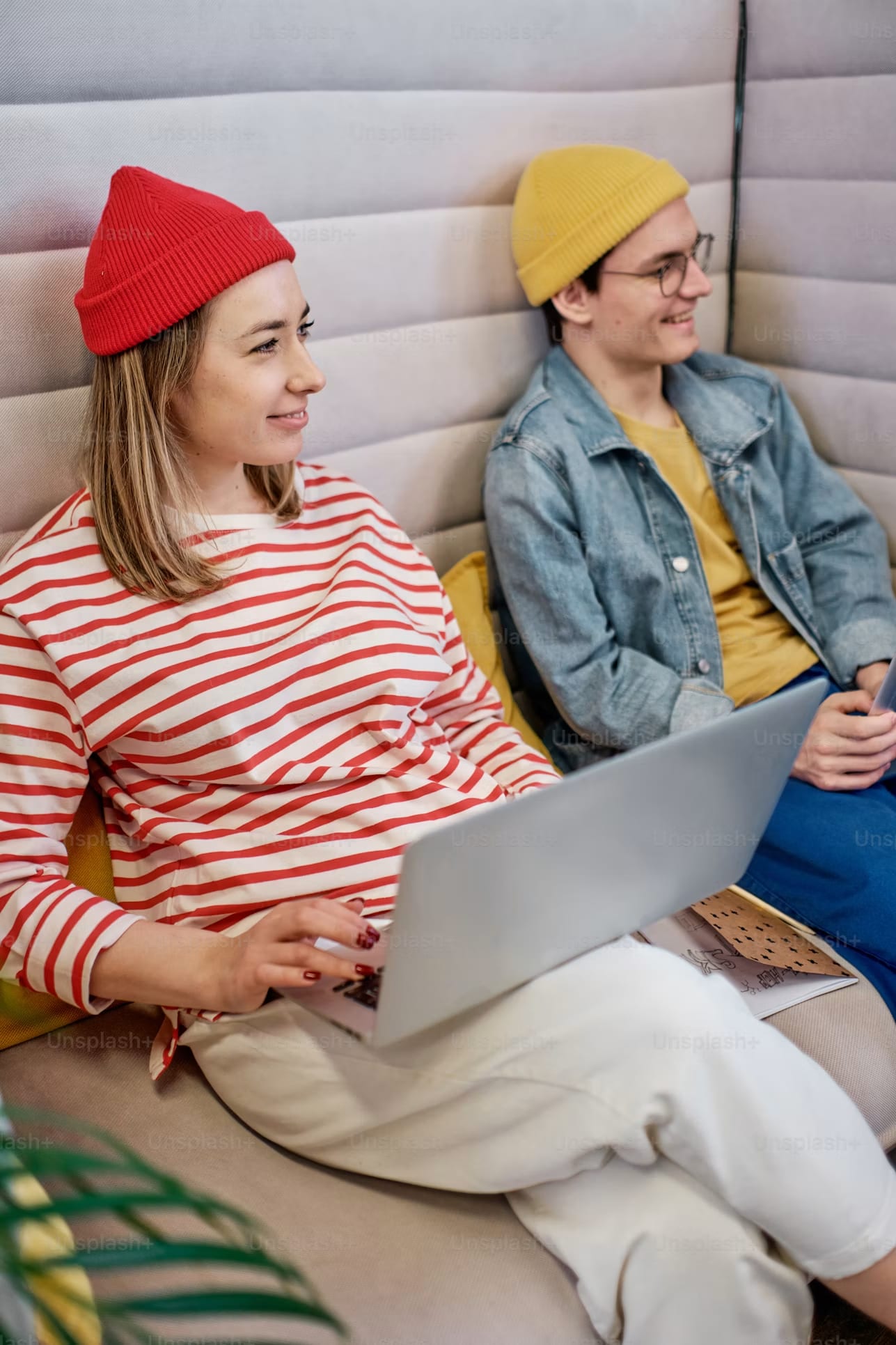 Two colleagues working on a laptop on a sofa