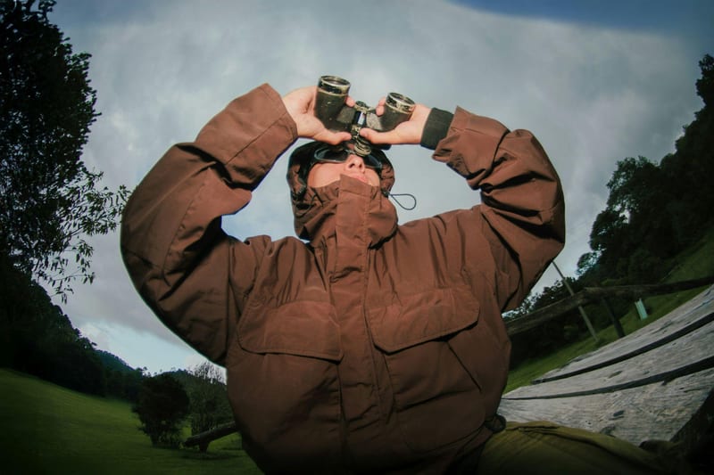 Person looking through binoculars in a forest