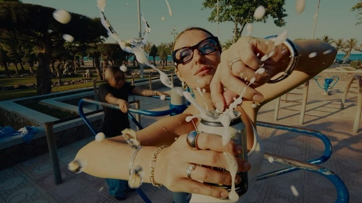 Person in sunglasses pulling a skateboard trick