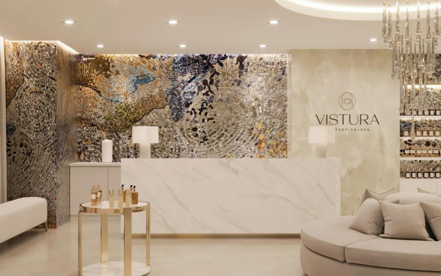 Luxurious Vistura Thetics + Spa reception with marble desk, mosaic wall, gold side table, and cream seating
