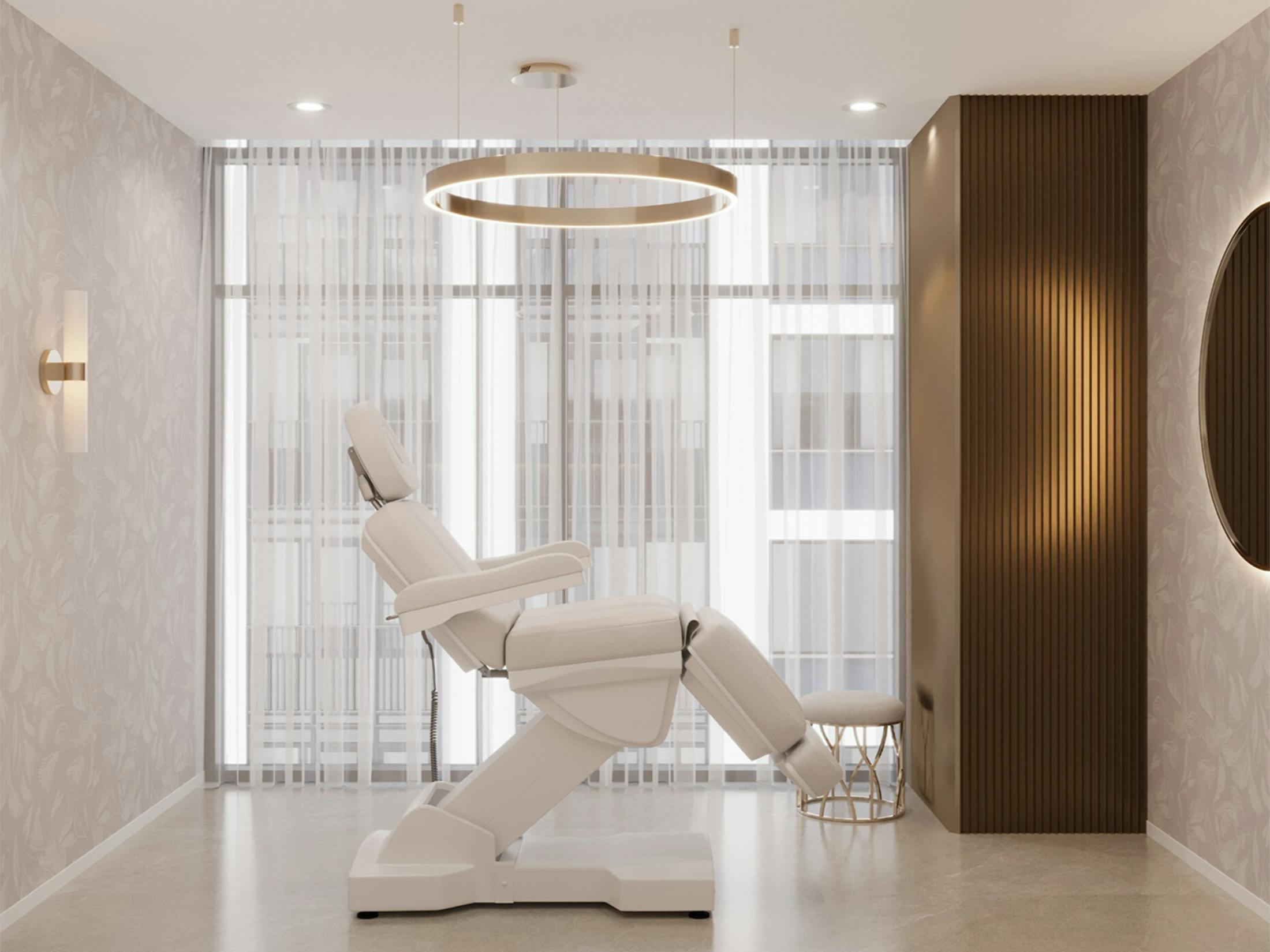 Reclining white treatment chair in a modern spa room with gold ring chandelier and sheer curtains