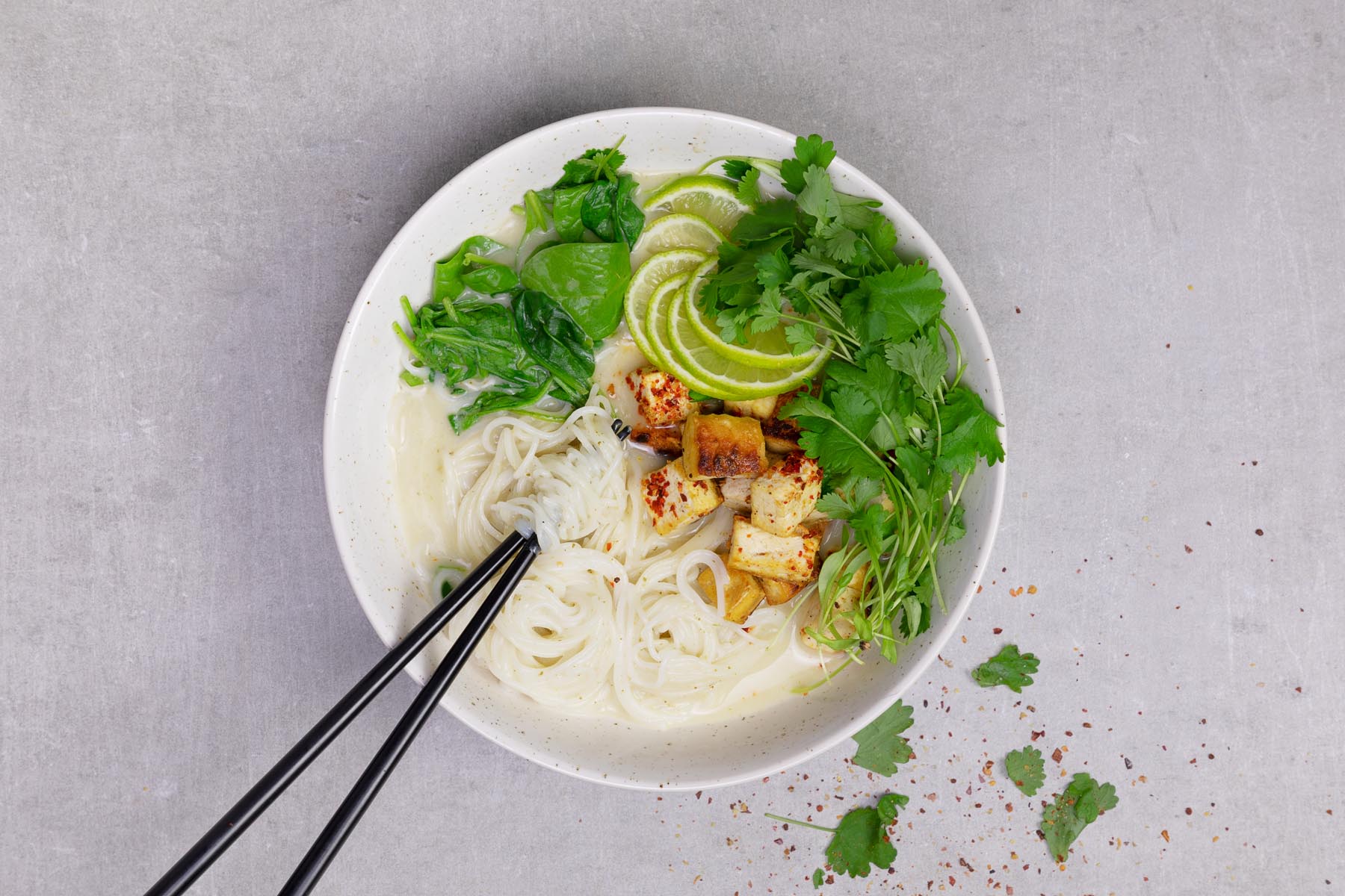 Fried tofu and green curry sit atop a bowl of rice noodles.