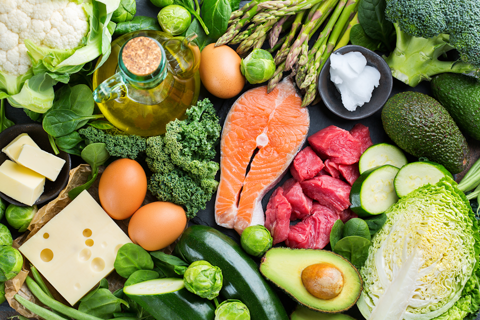 Assortment of ketogenic ingredients, such as green vegetables, meat, salmon, cheese and eggs.