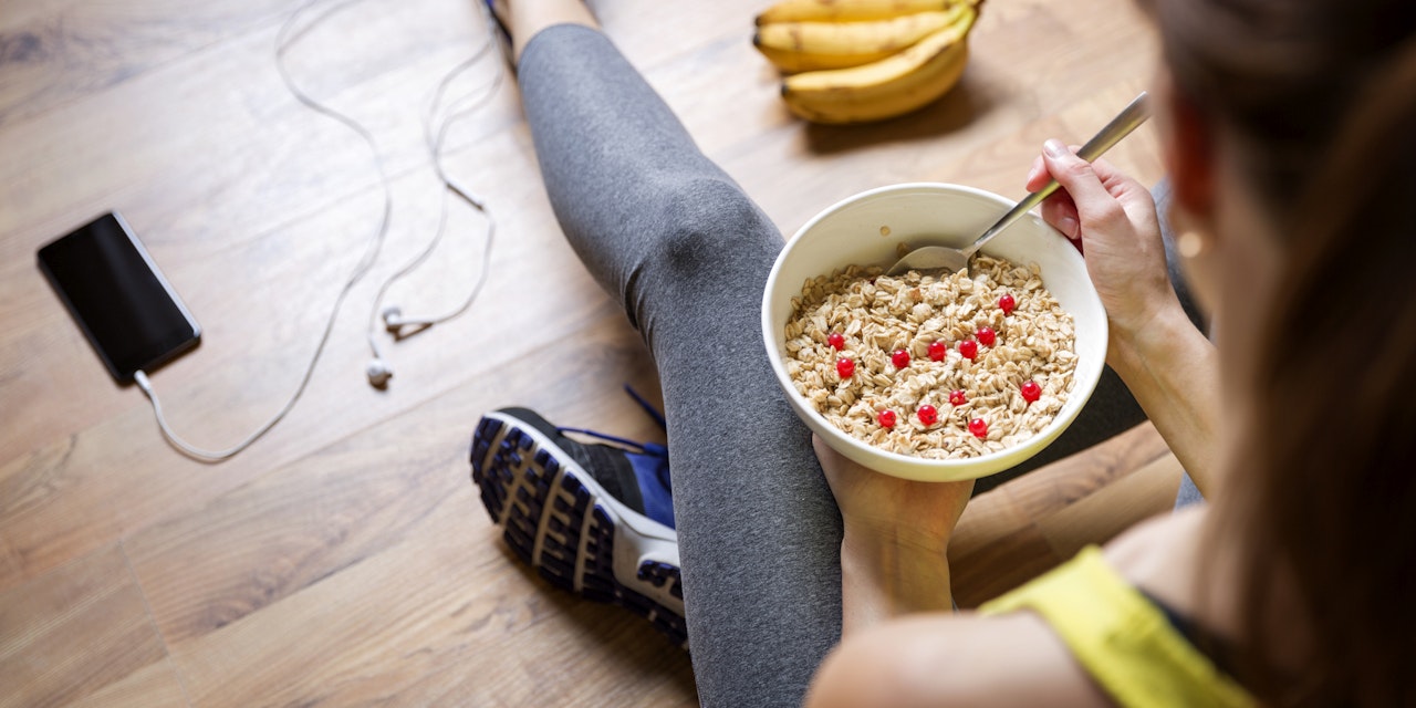 Woman eating oatmeal before working out Woman eating a bowl of oatmeal before working out