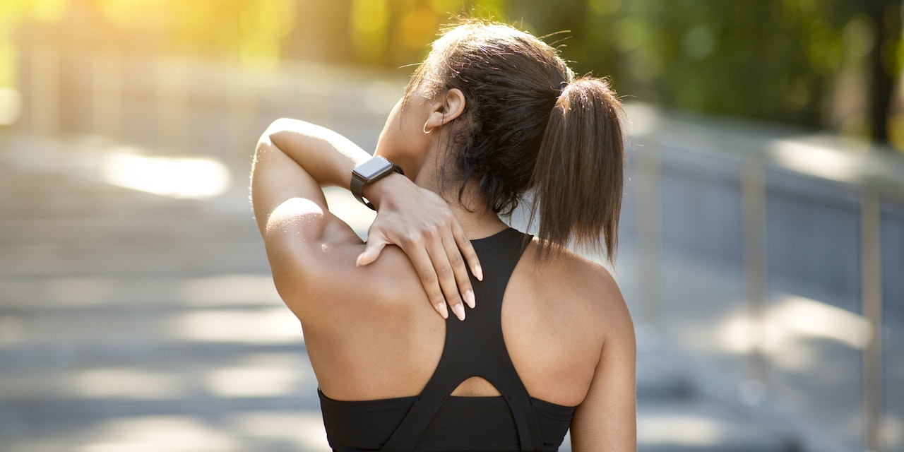 Woman with muscle soreness rubs her spine during traing