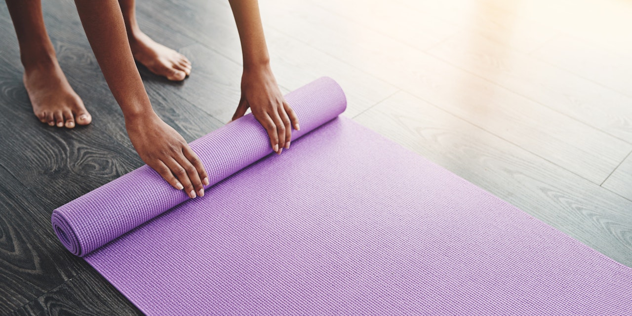 Person unrolling her yoga mat at the beginning of a flex class
