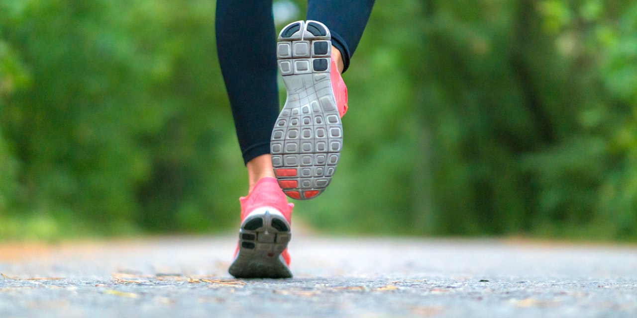 Close-up of sneakers of a running woman in the forest