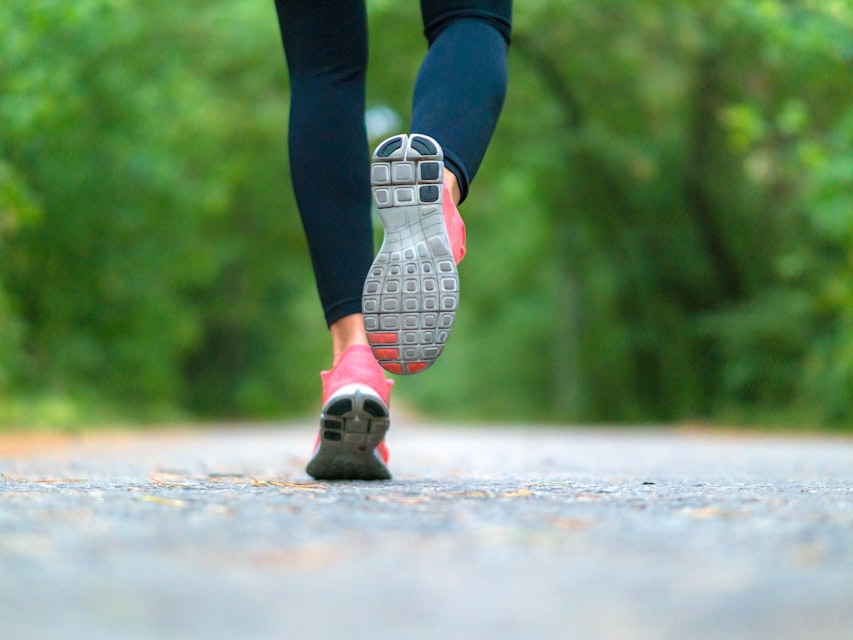 Close-up of sneakers of a running woman in the forest