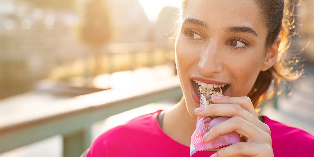 Woman eating protein bar during workout