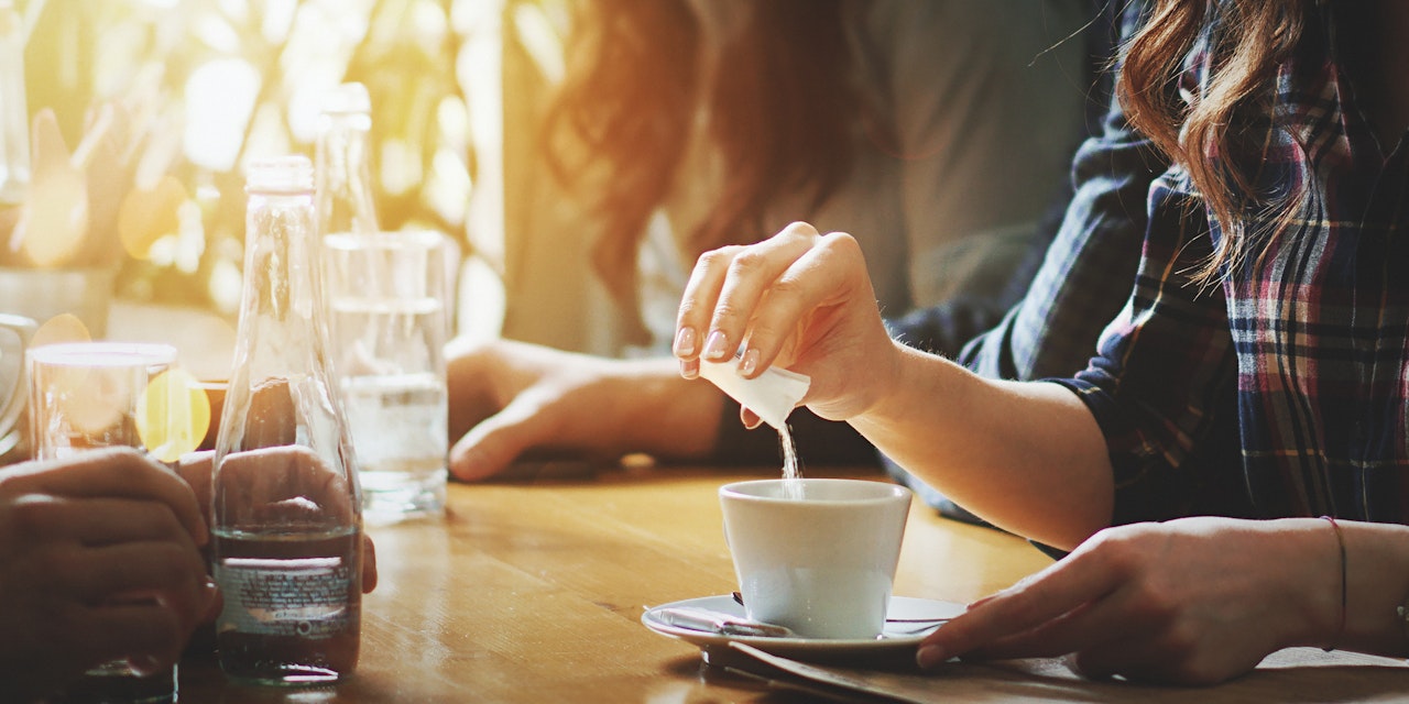 Woman putting sweetener in her coffee